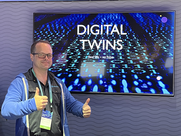 A man giving a thumbs up in front of a digital twins sign.