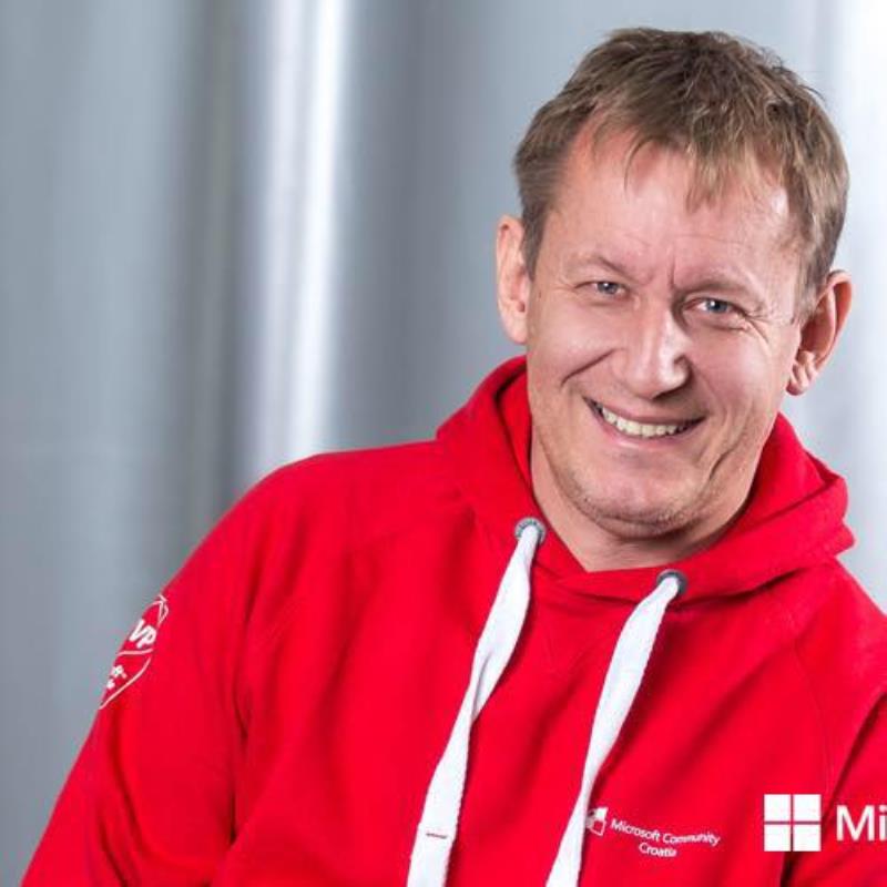 A man in a red hoodie smiling for the camera.